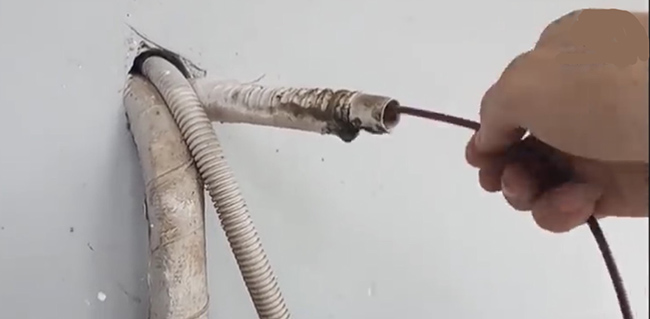 dùng dây điện chọc vào ống thoát nước thải máy lạnh để thông cho sạch